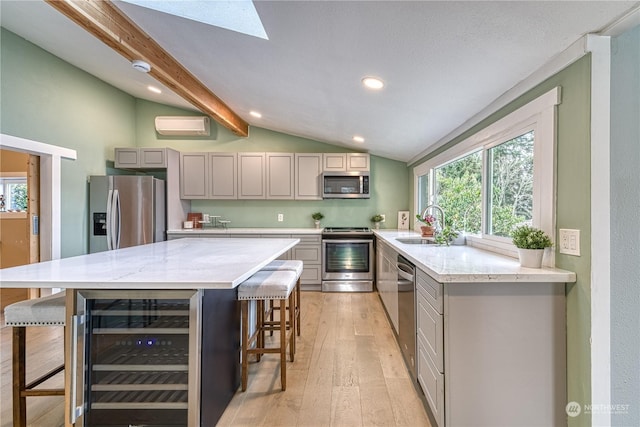 kitchen with stainless steel appliances, a kitchen bar, beverage cooler, gray cabinetry, and vaulted ceiling with beams