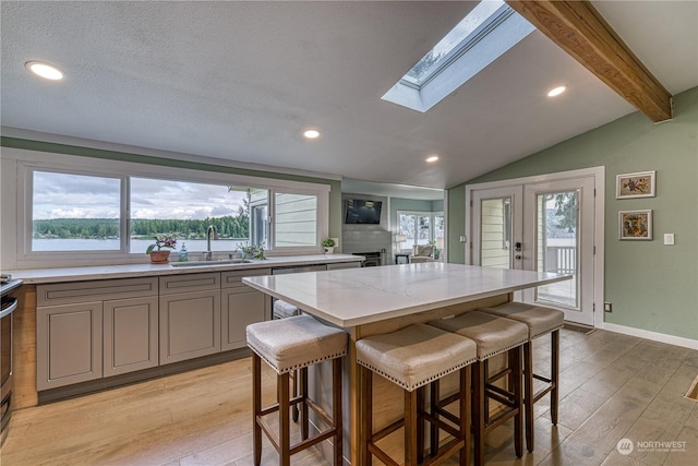 kitchen with a center island, light wood-type flooring, a kitchen breakfast bar, and sink