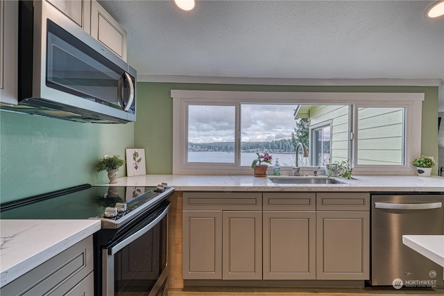 kitchen featuring appliances with stainless steel finishes, light stone counters, sink, and a textured ceiling