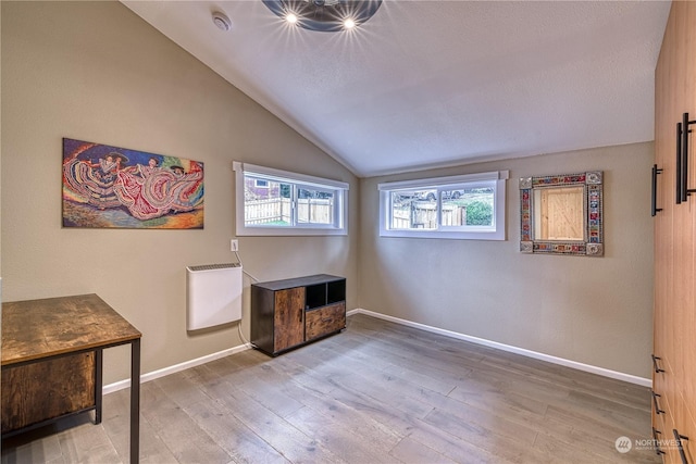 living area with lofted ceiling, heating unit, and hardwood / wood-style floors