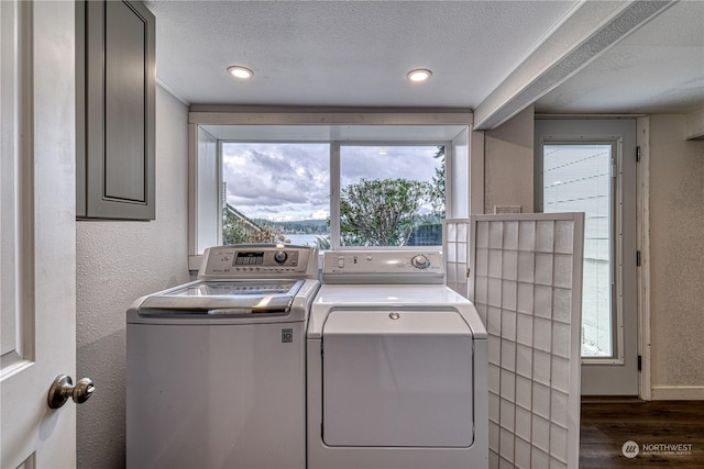 clothes washing area with a textured ceiling, plenty of natural light, washing machine and clothes dryer, and dark wood-type flooring