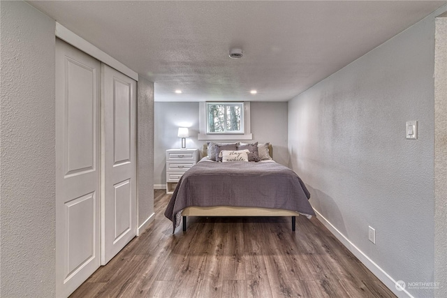 bedroom with a textured ceiling, a closet, and dark hardwood / wood-style floors