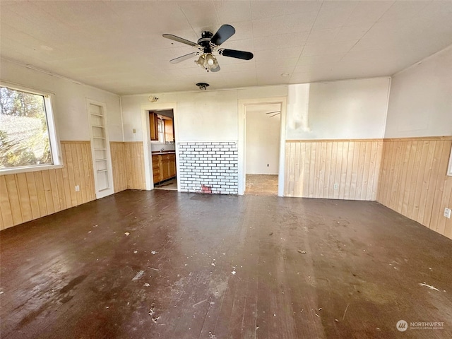 spare room with built in shelves, dark hardwood / wood-style flooring, and ceiling fan