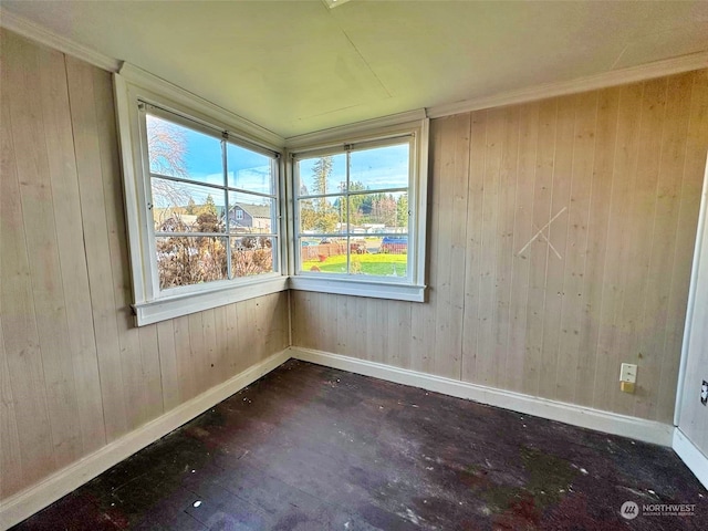 unfurnished room featuring crown molding and wood walls