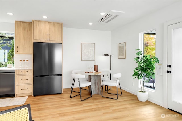 kitchen with backsplash, light brown cabinetry, light hardwood / wood-style flooring, and appliances with stainless steel finishes