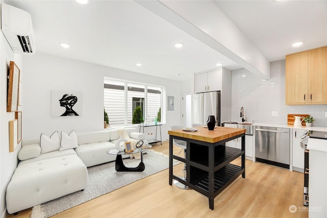 living room with sink, light hardwood / wood-style flooring, and a wall mounted AC