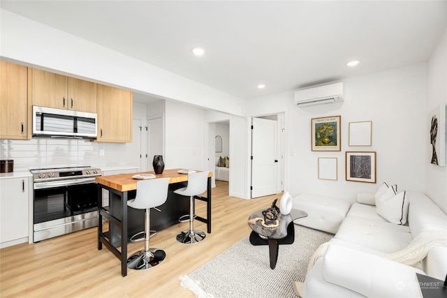 kitchen with decorative backsplash, appliances with stainless steel finishes, a wall mounted AC, light hardwood / wood-style floors, and butcher block counters