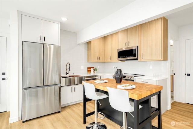 kitchen with white cabinets, sink, light wood-type flooring, and stainless steel appliances