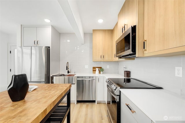 kitchen featuring appliances with stainless steel finishes, light wood-type flooring, backsplash, light brown cabinets, and white cabinetry