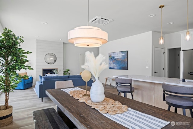 dining room featuring light hardwood / wood-style floors and a large fireplace