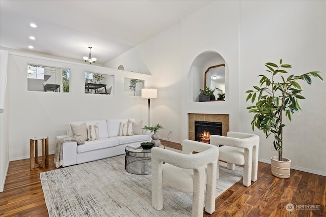 living room with a tiled fireplace, a notable chandelier, and dark hardwood / wood-style flooring