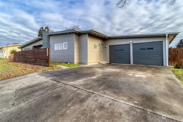 view of front of property featuring a garage, driveway, and fence