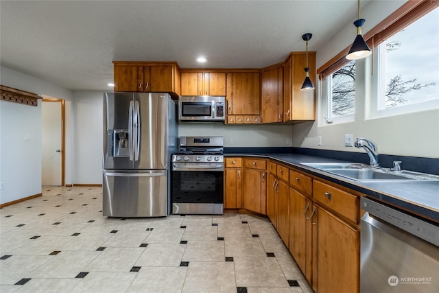 kitchen with appliances with stainless steel finishes, pendant lighting, and sink