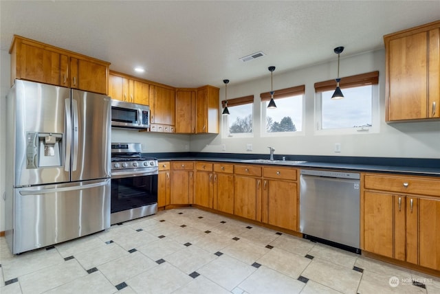 kitchen with decorative light fixtures, stainless steel appliances, a textured ceiling, and sink