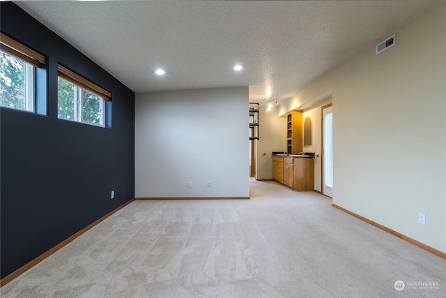 carpeted empty room featuring a textured ceiling