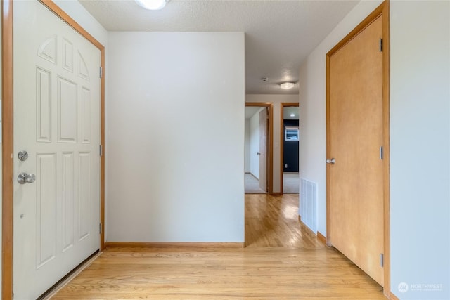 hall featuring a textured ceiling and light hardwood / wood-style flooring