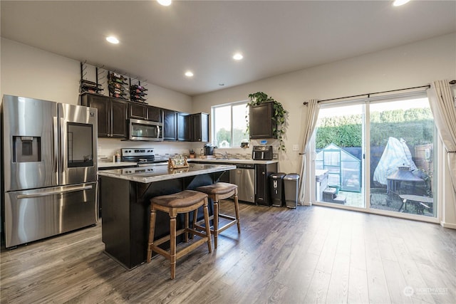 kitchen featuring stainless steel appliances, a kitchen breakfast bar, light wood-type flooring, a kitchen island, and sink