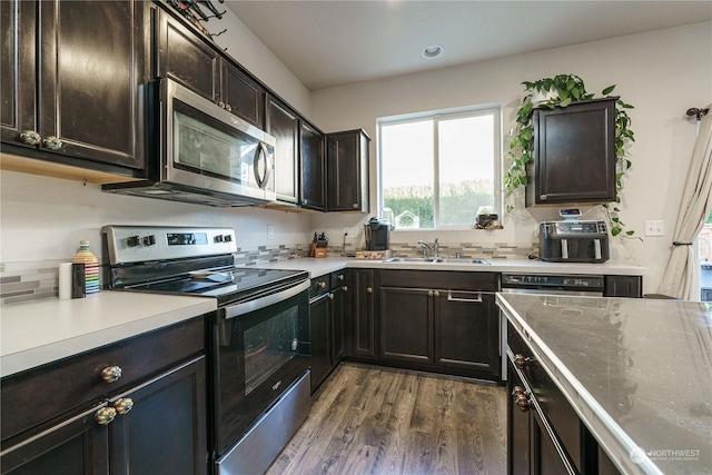 kitchen featuring dark wood-type flooring, sink, stainless steel appliances, and dark brown cabinets