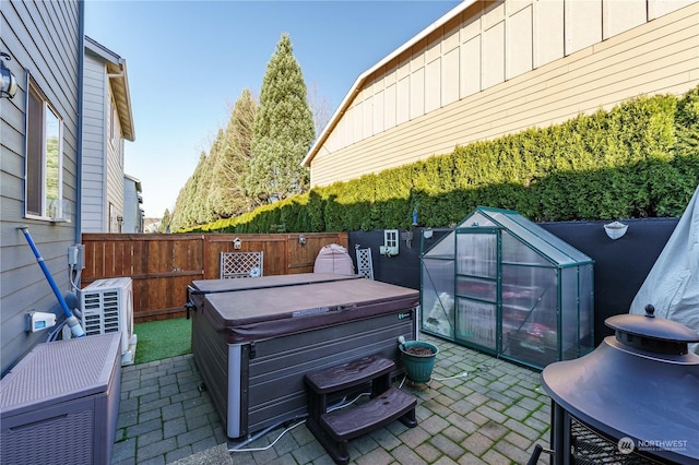 view of patio / terrace featuring ac unit, a hot tub, and an outbuilding