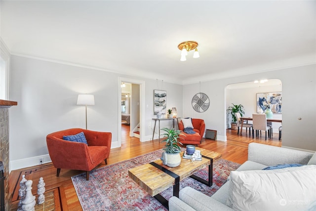 living room featuring crown molding, a fireplace, and wood-type flooring