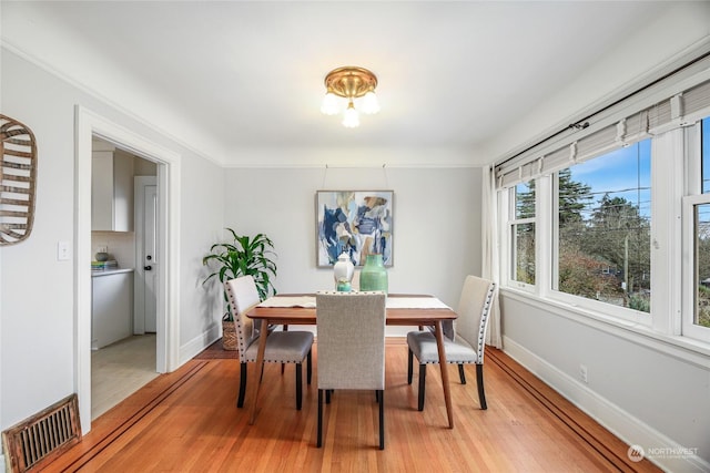 dining area with ornamental molding and hardwood / wood-style floors