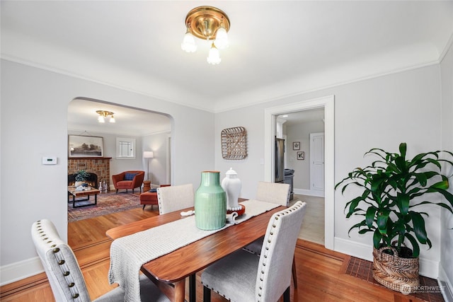 dining room featuring ornamental molding, a fireplace, and hardwood / wood-style flooring