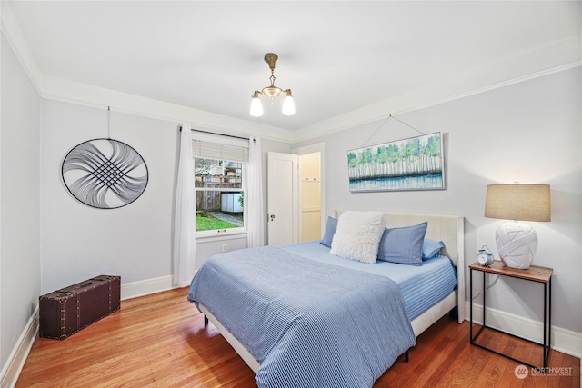 bedroom featuring hardwood / wood-style flooring, a notable chandelier, and crown molding