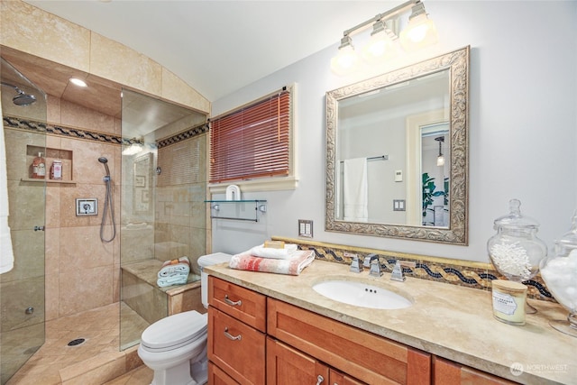 bathroom featuring a tile shower, lofted ceiling, vanity, and toilet