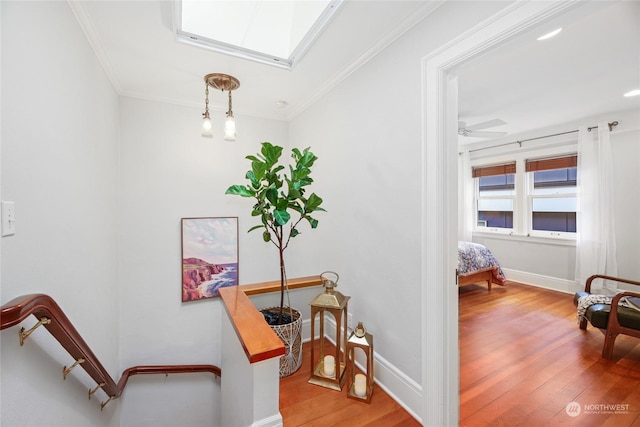 stairs featuring ceiling fan, ornamental molding, a skylight, and hardwood / wood-style floors