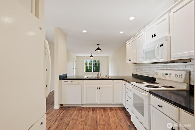 kitchen with dark countertops, white cabinets, and white appliances