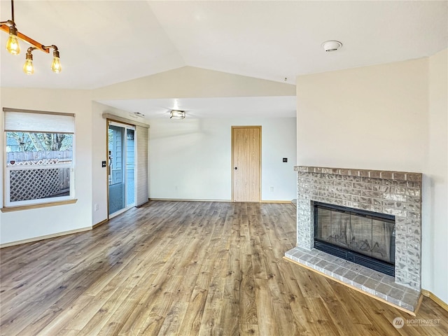 unfurnished living room with vaulted ceiling, a fireplace, and hardwood / wood-style flooring