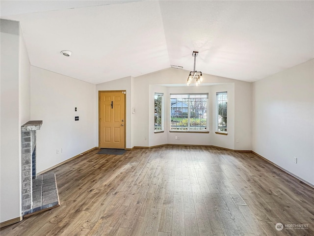 unfurnished living room with lofted ceiling, wood-type flooring, and a fireplace