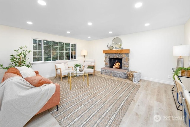 living room with light hardwood / wood-style flooring and a stone fireplace