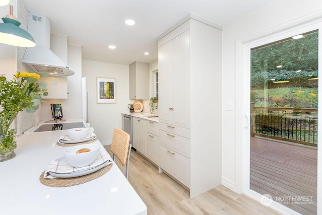 kitchen featuring white cabinetry, wall chimney range hood, light hardwood / wood-style flooring, stainless steel dishwasher, and black electric stovetop