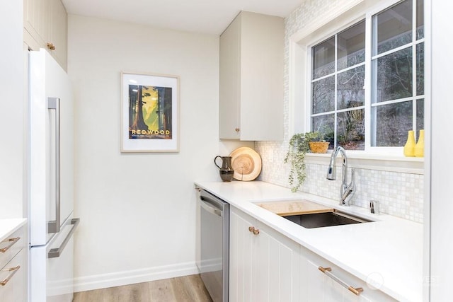 kitchen with sink, white cabinetry, dishwasher, light hardwood / wood-style floors, and high end fridge