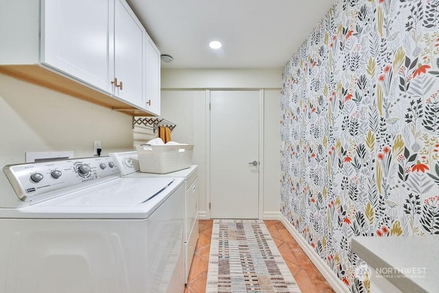 clothes washing area with washer and clothes dryer, light tile patterned floors, and cabinets