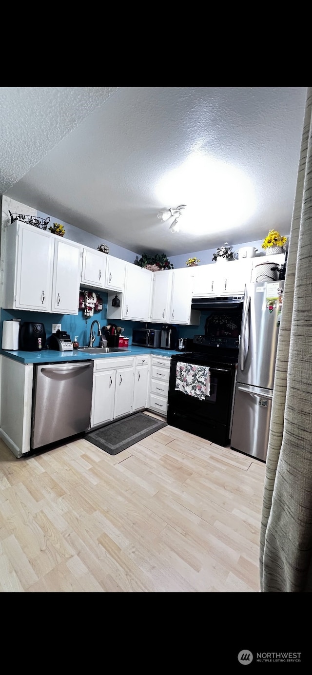 kitchen featuring appliances with stainless steel finishes, a textured ceiling, white cabinets, light hardwood / wood-style flooring, and sink