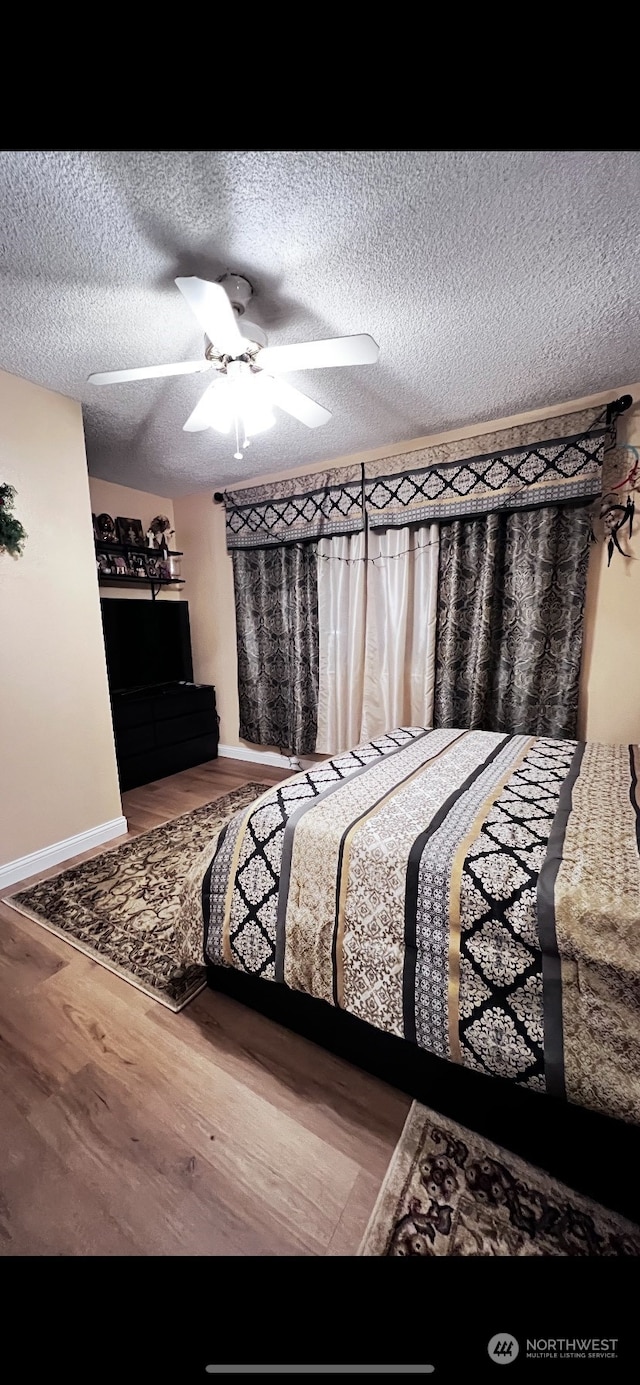 bedroom featuring wood-type flooring, a textured ceiling, and ceiling fan