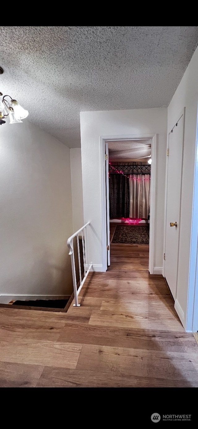 corridor featuring a textured ceiling and light hardwood / wood-style floors