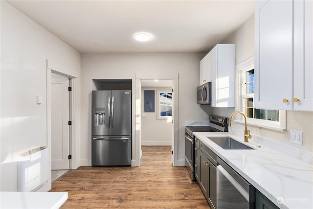 kitchen with light stone countertops, stainless steel appliances, light hardwood / wood-style floors, white cabinetry, and sink