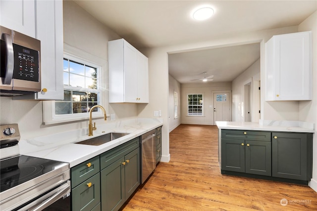 kitchen with green cabinets, light wood-type flooring, white cabinetry, appliances with stainless steel finishes, and sink