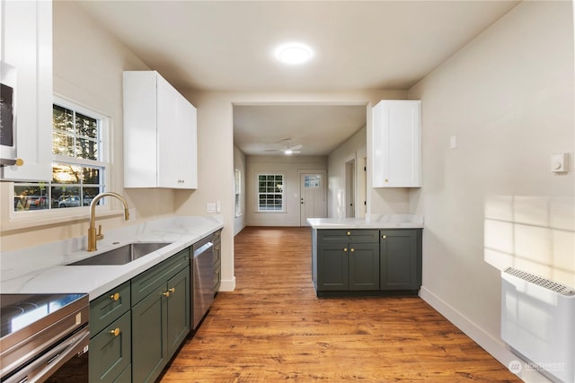 kitchen featuring white cabinets, heating unit, stainless steel appliances, light wood-type flooring, and sink