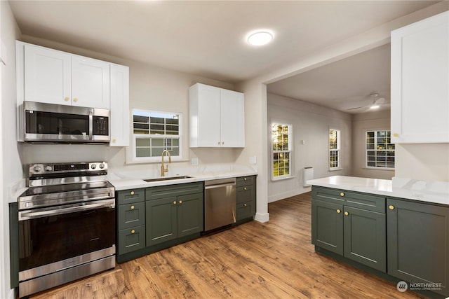 kitchen with white cabinets, wood-type flooring, stainless steel appliances, green cabinets, and sink