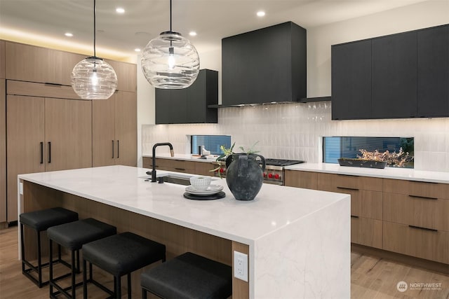 kitchen with a kitchen island with sink, sink, extractor fan, and decorative light fixtures