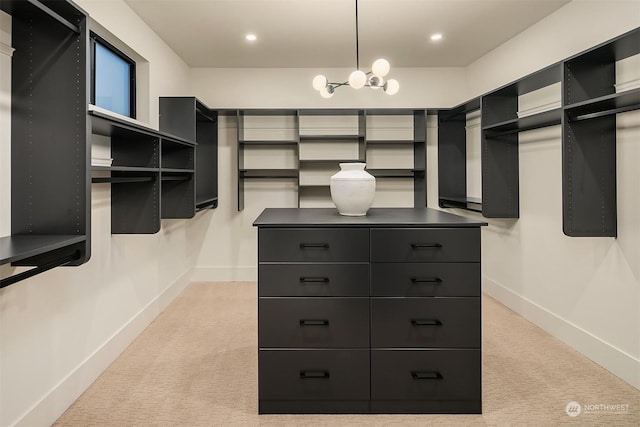 spacious closet with light carpet and an inviting chandelier