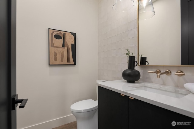 bathroom with hardwood / wood-style flooring, vanity, toilet, and tasteful backsplash