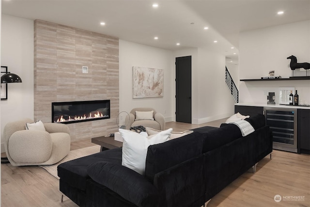 living room with wine cooler, indoor bar, light hardwood / wood-style floors, and a tile fireplace