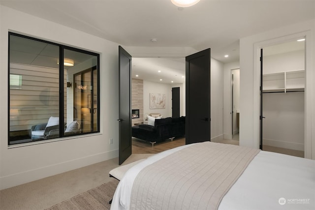 carpeted bedroom featuring a walk in closet, a fireplace, and a closet