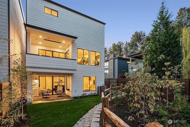 back house at dusk with a yard, a patio area, and central air condition unit