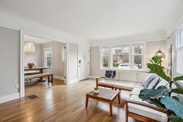 living room featuring crown molding and light hardwood / wood-style flooring